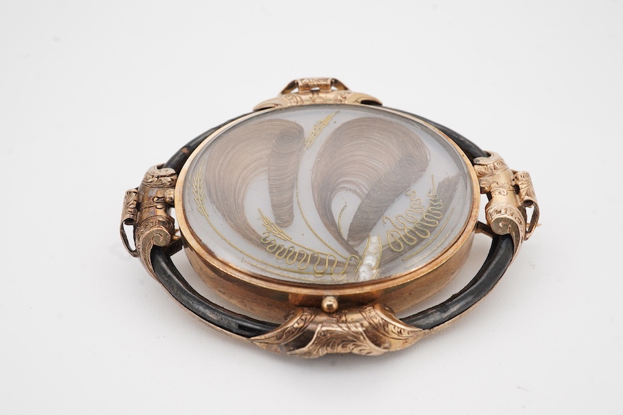 A Victorian yellow metal and black enamel oval mourning brooch, with plaited hair beneath a glazed panel, the back inscribed 'In Memory of Alex Rae died 21st Aug. 1848, A.B.', 53mm.